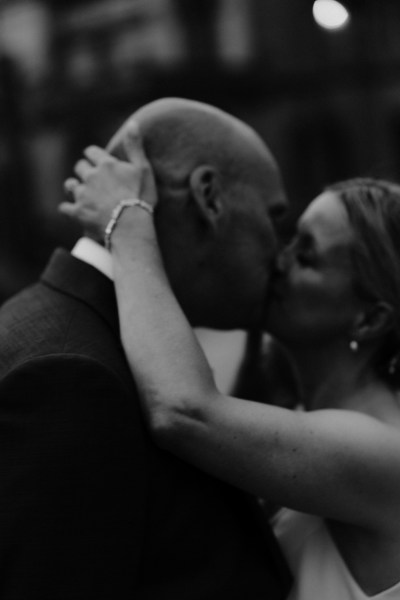 Bride and groom kissing kiss in front of castle house manor hotel wedding venue black and white image