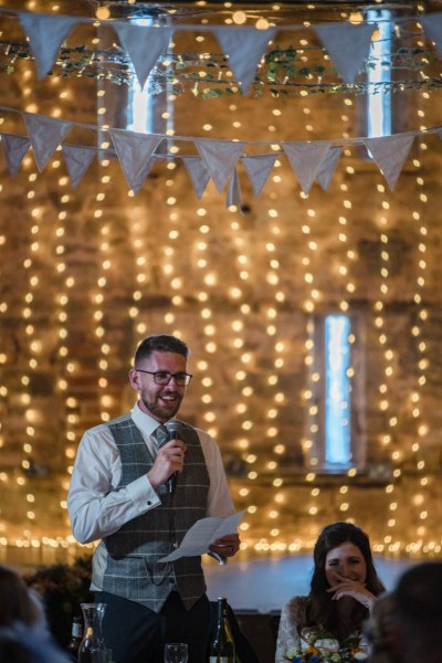 Groom gives speech orange bright lights in background