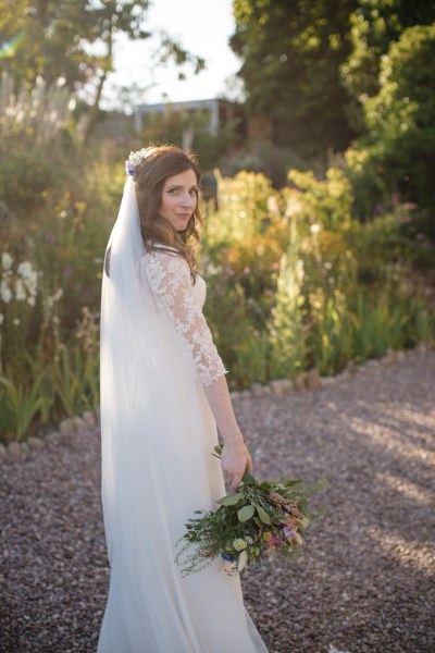 Bride looks over her shoulder on pathway