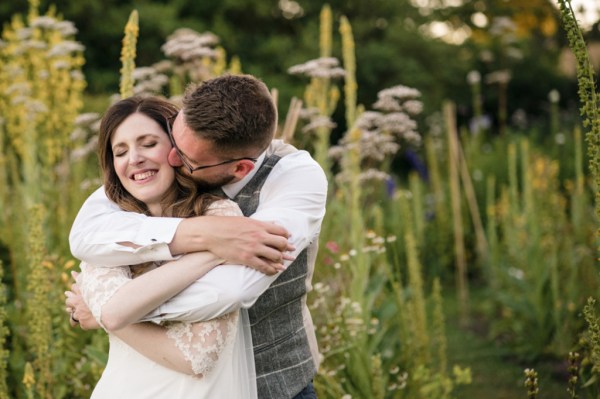 Groom kisses bride on the cheek in garden