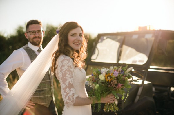 Bride with groom in garden holding bouquet