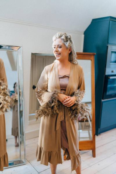 Bridesmaids with their hair being curled getting ready in front of mirror