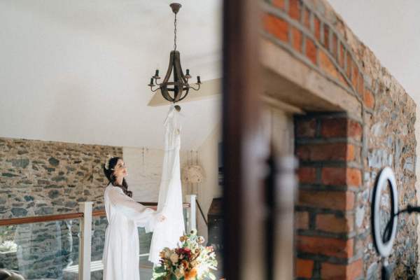 Bride and bridal gown dress hanging on chandelier