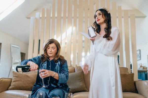 Mother pours glass of champagne bride stands