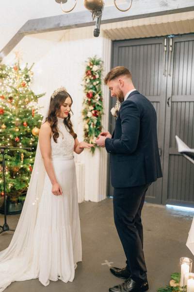 Groom places wedding band on brides wedding finger