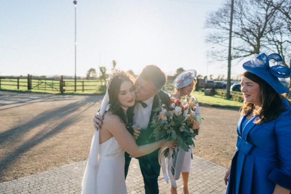 Father kisses daughter on the cheek holding bouquet