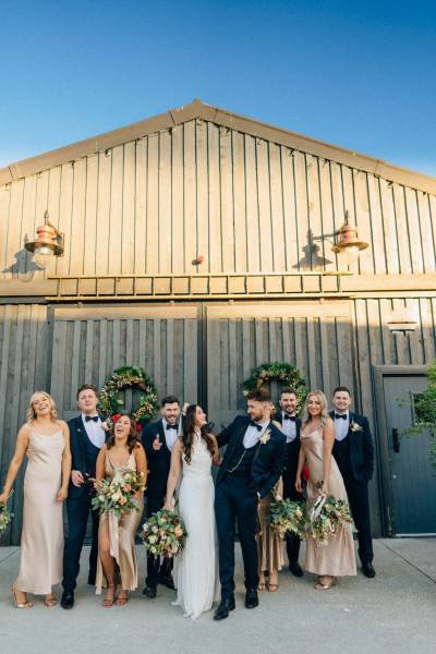 Bride groom bridesmaids groomsmen in front of barn door exterior