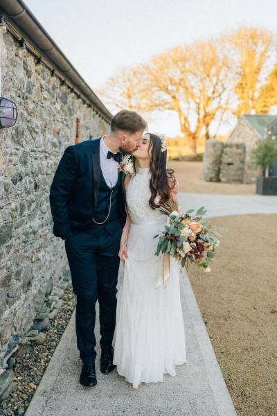 Bride and groom kiss outside in courtyard to hotel/venue