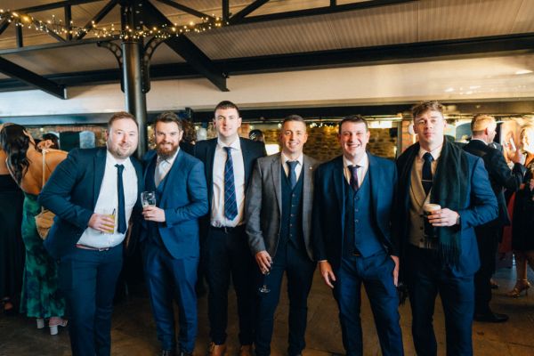 Men guests holding beer pose for a picture