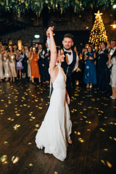 Bride and groom enter ballroom hands in the air first dance dancefloor