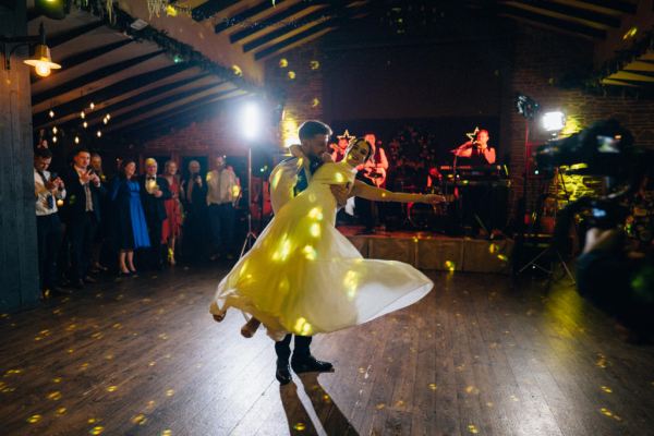 Bride and groom enter ballroom hands in the air first dance dancefloor