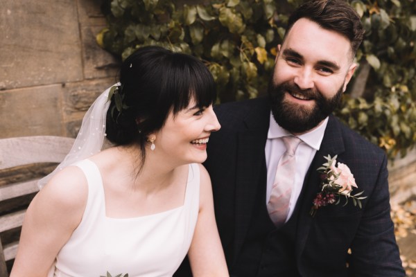 Bride and groom sitting on bench both smiling