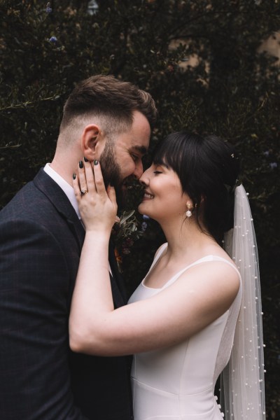 Bride and groom hand on cheek smiling