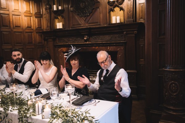 Guests mother father and bride clap at the table