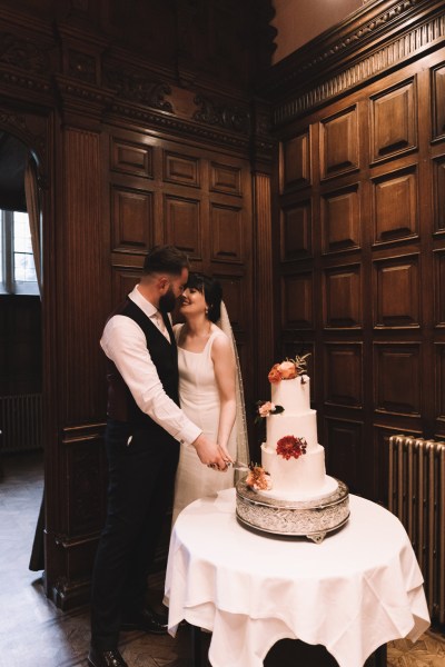 Bride and groom cut the wedding cake flowers on top