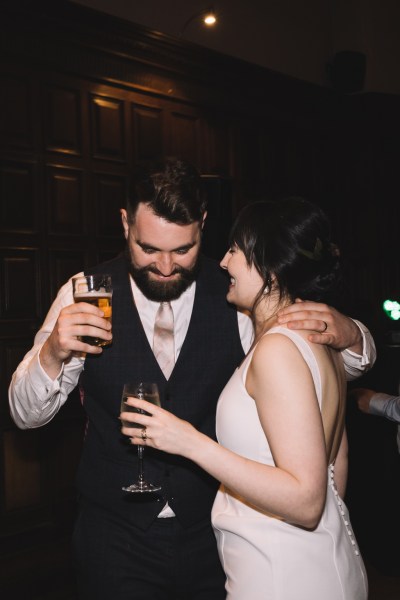 Groom holding pint of beer with bride