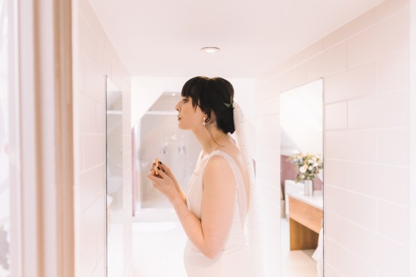 Bride puts her lipstick on in mirror makeup