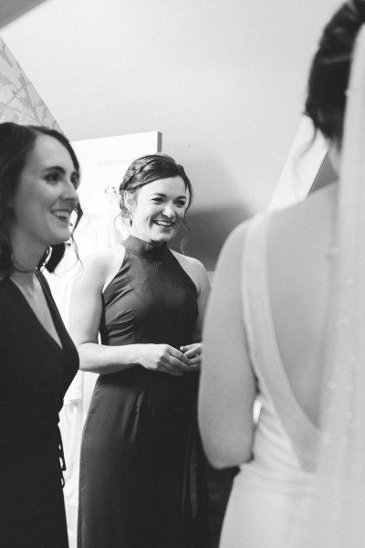 Two bridesmaids and the bride smile and laugh together