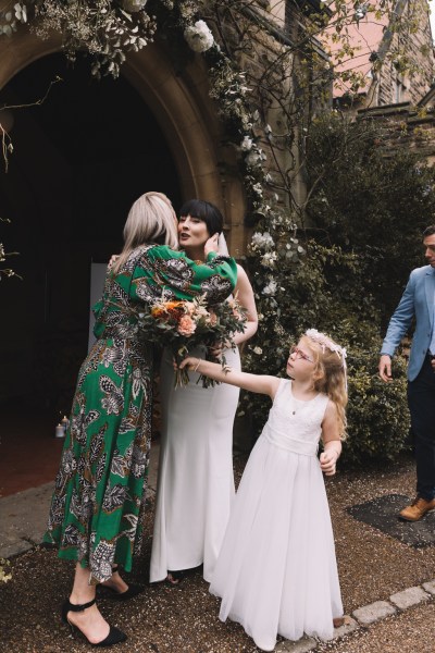 Groom hugs woman little girl in shot