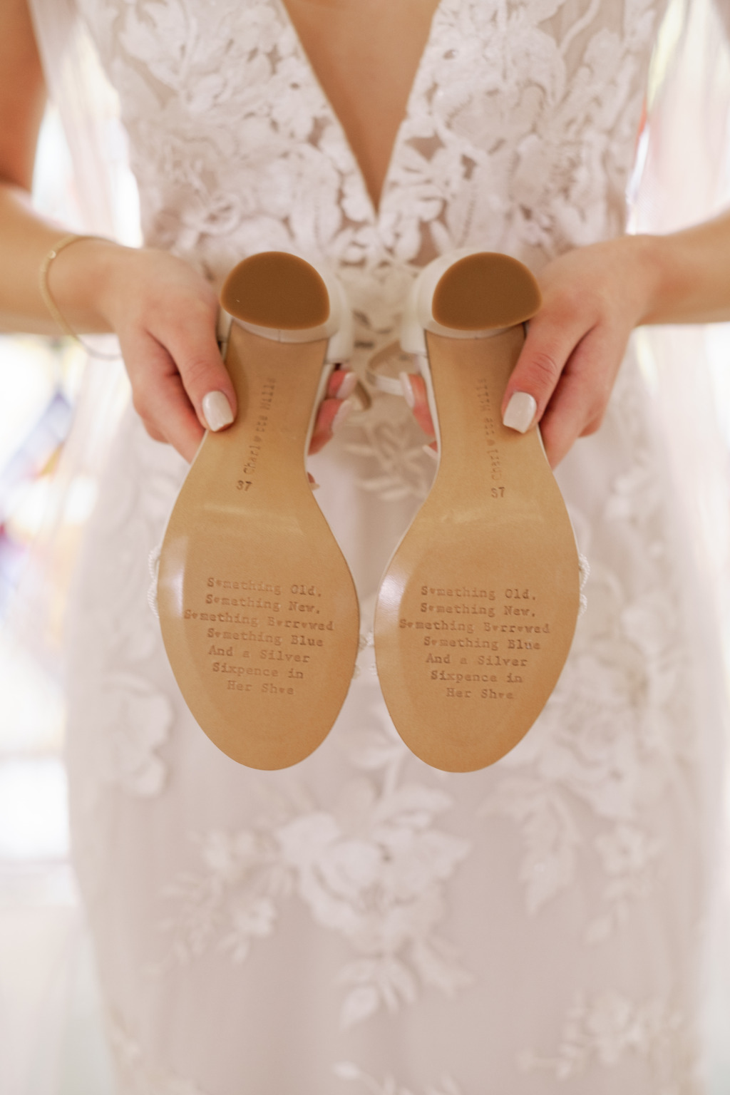 Bride holds feather heels bridal shoes shows off the back of them