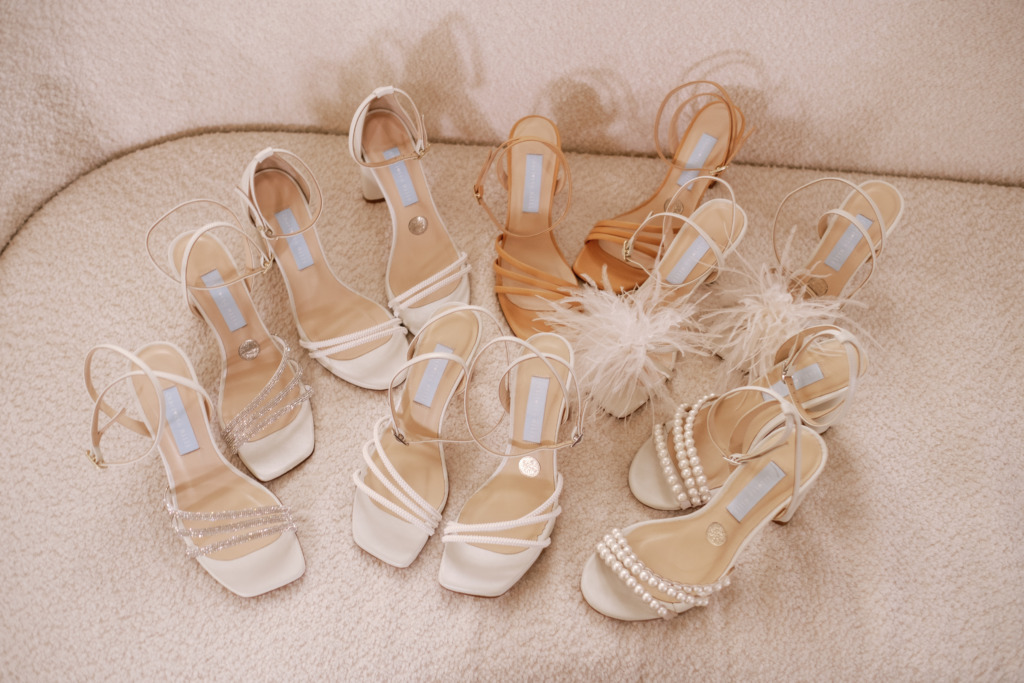 Series of strapped white bridal heels shoes lying on couch