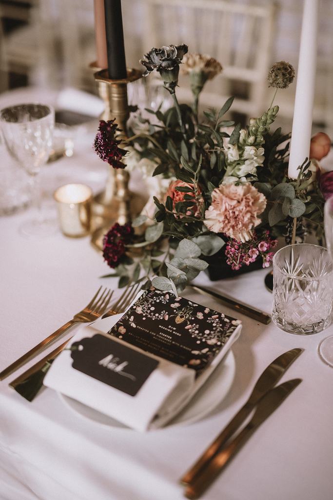 Table and chairs for guests roses flowers candles wine glasses and menu