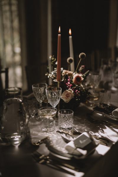 Close up flowers bouquet detail roses and candles on table whiskey and wine glasses