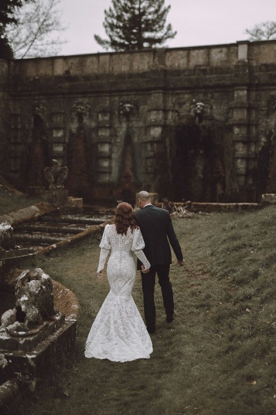 Bride and groom walking along the grass forest park setting