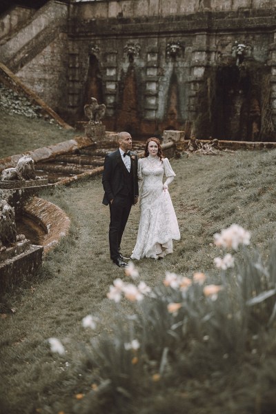 Bride and groom walking along the grass forest park setting grass and flowers