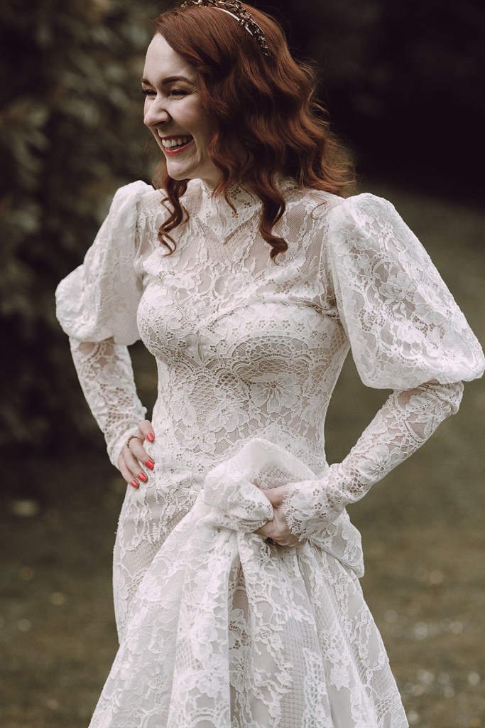 Bride on her own holds up her dress to walk