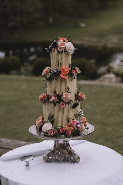 White wedding cake covered in flowers on table