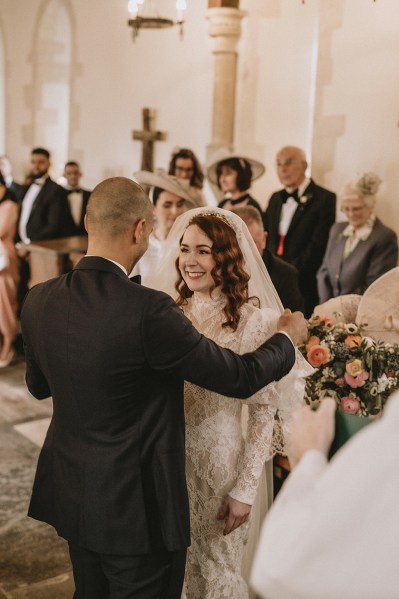 Groom takes veil off brides face they smile