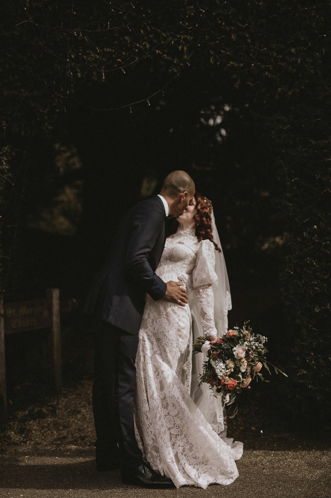 Bride and groom kiss as she holds bouquet of flowers