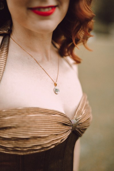 Up close detail of woman in brown velvet dress and gold chain necklace