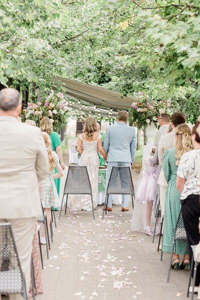 Bride and groom hold hands at alter in front of guests during ceremony