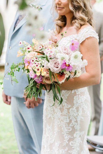 Close up of brides bouquet colourful flowers holding hands with groom