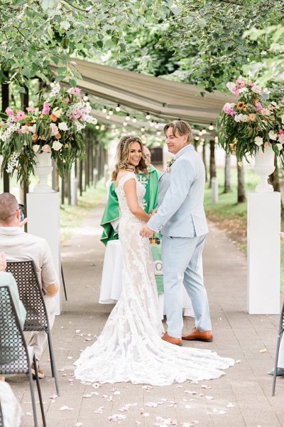 Bride and groom look over shoulder during ceremony standing at alter with celebrant