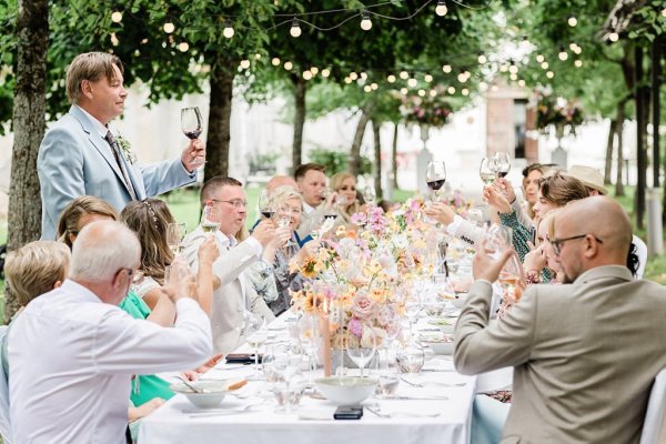 Bride and groom raise their wine glasses red and white guests