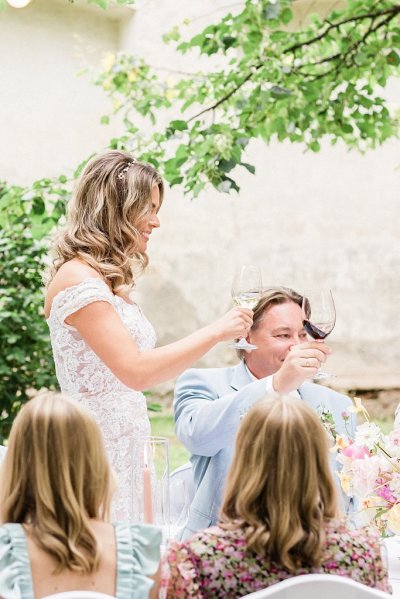 Bride and groom raise their wine glasses red and white guests