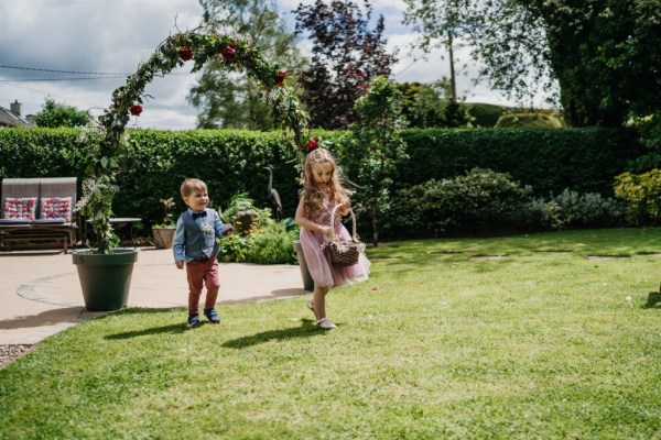 Little girls running on grass outside in garden