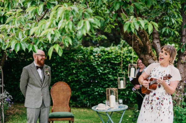 Bride playing guitar candles and tree in background she's singing