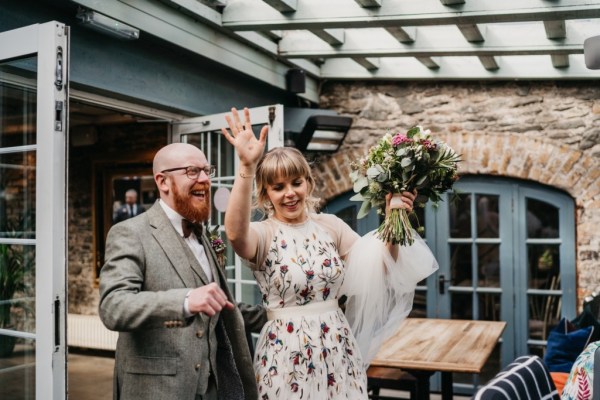 Hands in the air bride and groom holding bouquet