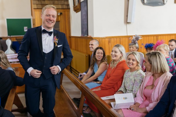 Groom enters church guests smiling laughing