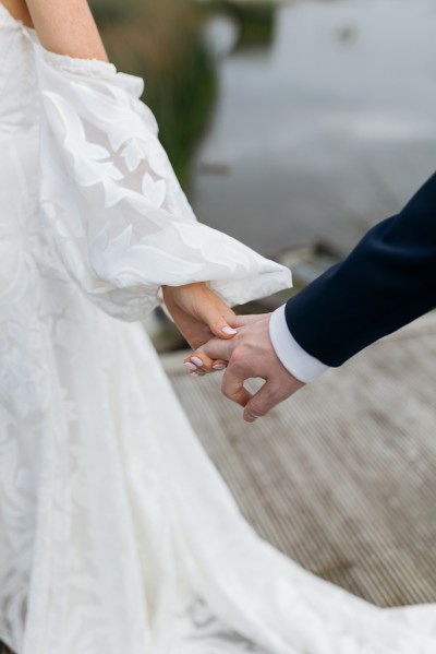 Close up of bride and groom holding hands