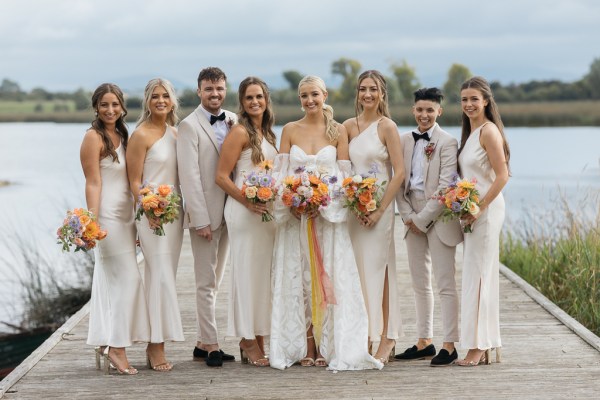 Group shot of bride groom bridesmaids groomsmen posing outside for photo