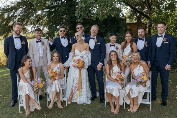 Portrait shot of family bride groom groomsmen best man bridesmaids maid of honour pose on grass