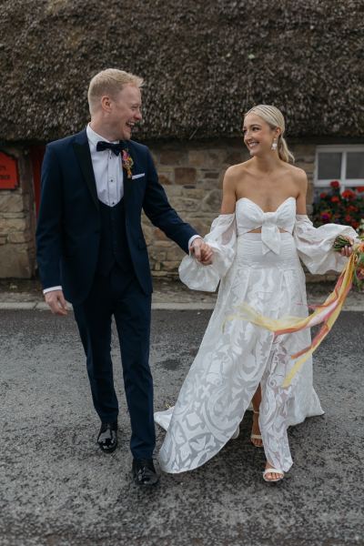 Bride and groom hold hands on the road