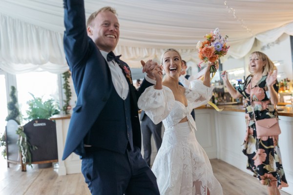 Bride and groom enter ballroom with guests