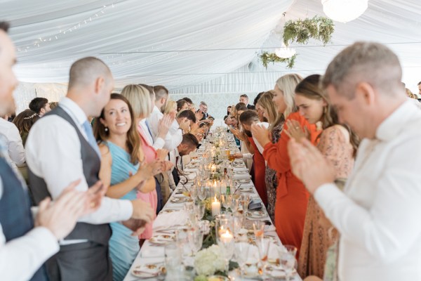 Guests at table clapping for couple