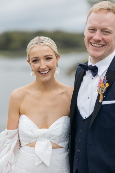 Bride and groom laugh on the boardwalk bouquet in shot lake in background